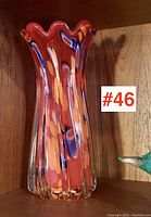 Photo of large art glass vase with ruffled top and colorful orange, blue, and red mottled pattern, showing full height and shape.