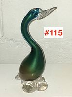 Side profile of Murano glass duck sculpture with green aventurine copper body and clear glass base and beak.