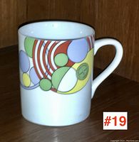 Front angled view of the porcelain mug showing colorful geometric circular design and white handle.