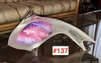 Angled side view of the frosted glass fish showing clear glass dorsal fin and colorful internal design in purple and pink.