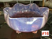 Front angle showing the scalloped rim and opalescent gradient from cranberry to purple on the glass bowl sitting on glass feet.