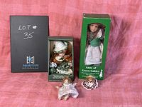 Photo of all four dolls including boxed Anne of Green Gables doll, boxed Jenny doll, and two small loose porcelain dolls on a pink background.