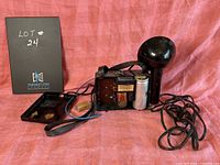 Braun electric flash unit with exposed internal components, wiring, and strap laid out on pink fabric background.