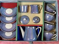 Photo showing entire tea set in original box packaging, including teapot, creamer, sugar bowl with lid, four cups and four saucers arranged in compartments.