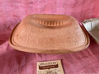 Romertopf brand name and intricate embossed design on lid of clay baker.
