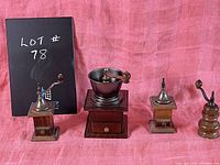Photo showing all four coffee grinders together against a pink fabric background with a lot number sign.