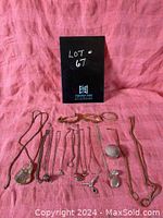 Photo showing assortment of costume jewelry items arranged on a pink fabric background with a black lot number card.