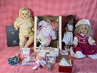 Wide shot showing entire grouping of dolls and dollhouse toys on pink background