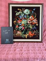 Frontal view of vintage floral petite pointe needlepoint framed artwork on pink fabric backdrop with lot number card.