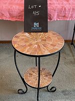 Front view of round side table showing shell tile top surface and curled metal feet