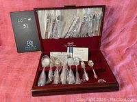 Full view of the Rogers silverplate cutlery set for 12 displayed in original wooden case with red velvet lining, all pieces individually wrapped in plastic.