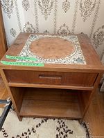 Front view of the teak wood night table showing the drawer and cubby area beneath the tiled top.
