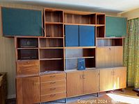 Full front view of entire modular teak wall unit with cabinets, shelves and speakers installed.