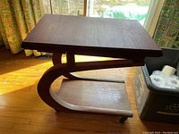 Side view of tea caddy showing curved support legs and caster wheels