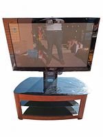 Samsung 40-inch TV with stand featuring tempered glass top. Black frame TV and wooden stand with glass shelves shown in natural lighting.