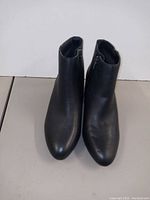 Front view of the pair of black leather ankle boots showing the rounded toe and smooth leather finish.