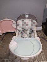 Child's high chair with padded seat cushion in checkered pattern, featuring mouse applique on backrest, and light blue detachable feeding tray in front.