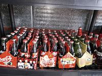 Large collection of Coca-Cola glass bottles in original packaging displayed on shelving.