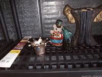 Decorative figurines including metallic bird sculpture, mouse drummer, ceramic crown, and bird figurine