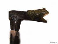 Close-up photo of the handcrafted cane's T-shaped handle with a carved and painted frog figure on top.
