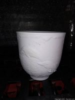 White porcelain bowl with embossed dolphins on its side, showing detailed dolphin shapes and water texture effect.