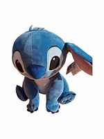 Large blue Stitch plush shown outdoors with one ear flipped, showcasing the original tag.