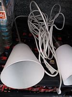 Photo showing two white cone-shaped drop lights with cords coiled, placed on crates
