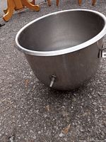 Side view of stainless steel mixing bowl showing spout near base and handle on the side