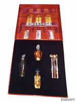 Four mini glass Givenchy perfume bottles in an insert with a Givenchy illustrated cover behind them in a red box.