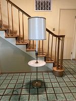 Full view of vintage petite floor lamp showing marble tabletop and brass base with white lampshade.