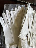 Pair of vintage white gloves with plain design and textured cuff detail, one pair displayed in plastic sleeve