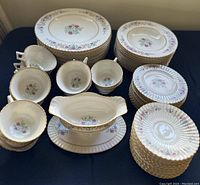 Overhead view of stacked dinner, salad and bread plates, bouillon cups and gravy boat on table