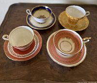 Four Ansley cups and saucers in different colors and patterns, shown arranged on a tray.