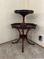 View of entire 2-tiered mahogany stand showing leather top tier and wooden bottom tier on carpeted floor.