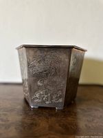 Front side of metal incense burner pot showing an engraved crane standing next to a pine tree.