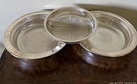 Lot of three plated silver bowls; one segmented bowl with glass lid in center flanked by two plain round bowls.