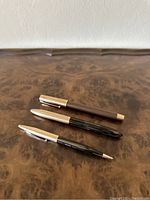 Full set includes one pen and one pencil on brown wood surface.
