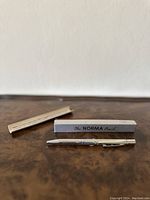 The Norma mechanical pencil alongside its original box and instruction leaflet on a wooden surface