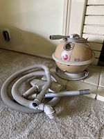 Photo of beige spherical Hoover Constellation vacuum with cord and cleaning hose with attachments.