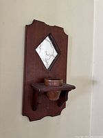 Full front view of the vintage wooden wall sconce showing the diamond shaped mirror and candle holder shelf.