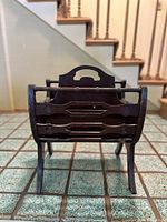 Front view of the vintage wooden magazine rack showing side panels, handle, and legs.