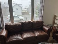 Photo of deep burgundy/brown genuine leather 3-seater sofa showing front view with three seat and back cushions, padded armrests, and leather surface with some visible wear.