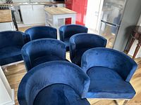 Four navy blue velvet chairs arranged in a kitchen/dining area. Each has a rounded backrest and chrome base, shown from a top and front perspective to display upholstery and structure.