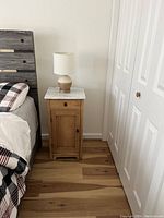 End table beside bed, showing marble top, drawer and cabinet door