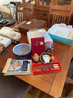 Full view of the set including bowls, chopsticks, mask, Buddha figurine, maps, and containers on wooden table
