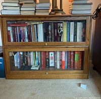 Front view of the wooden barrister bookcase filled with books, showing two glass doors and wooden frame.