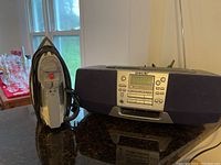 Sony CFD-S38 boombox and Proctor Silex iron side by side on a dark countertop in front of windows.