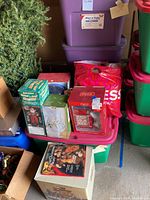 Photo showing multiple storage bins stacked with various boxed holiday candle holders and Coca-Cola collectibles.
