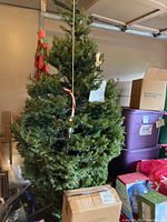 Full artificial Christmas tree standing upright in garage area showing height and built-in lights.