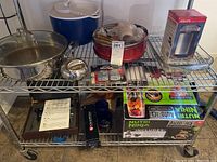 Metal wire shelf rack holding cookware, kitchen items, and boxed coffee grinder